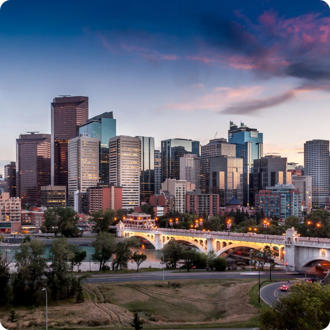 City of Calgary downtown skyline with tall buildings and a bridge at dusk.