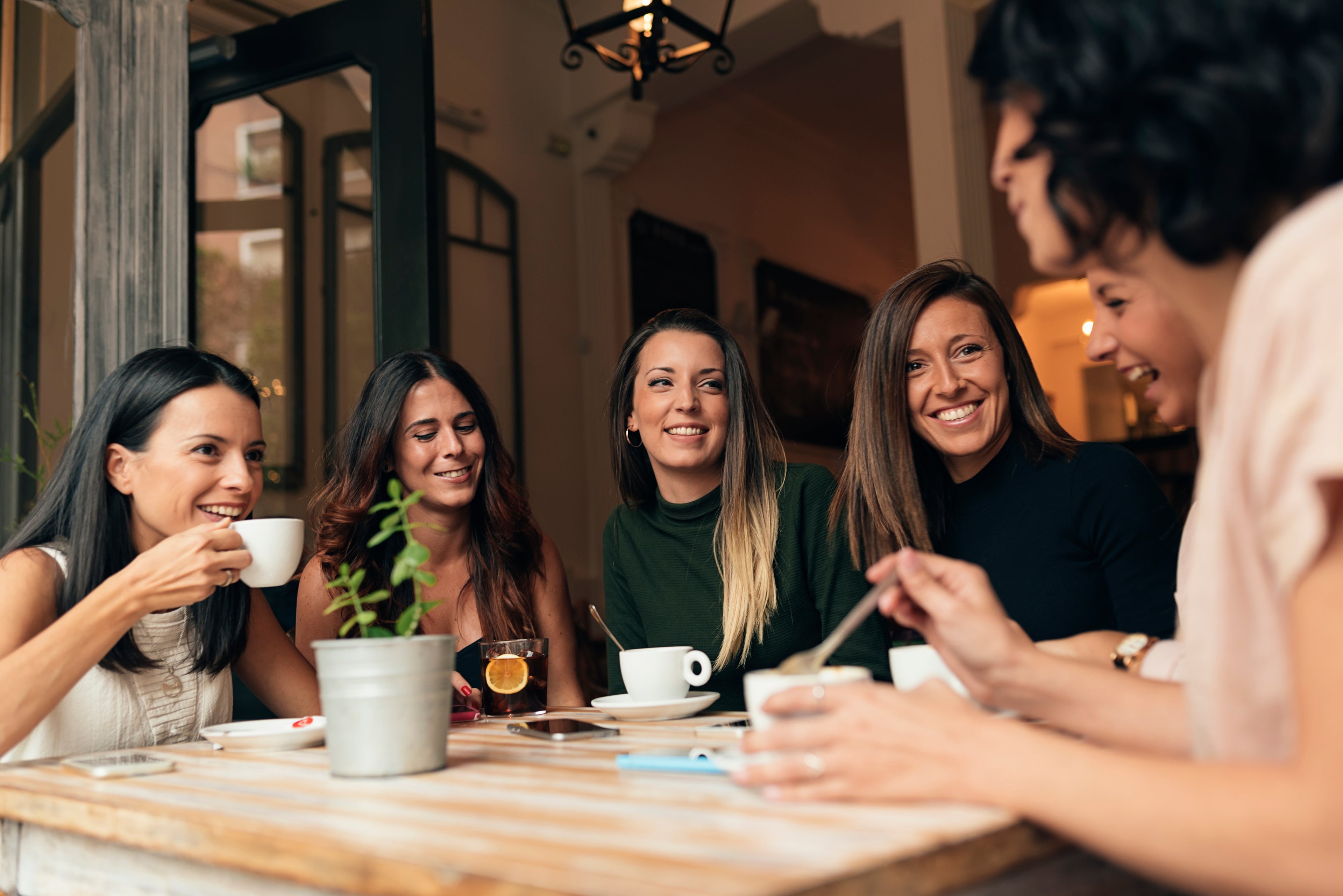 Group of women sitting around a table, enjoying coffee and conversation in a cozy cafe.