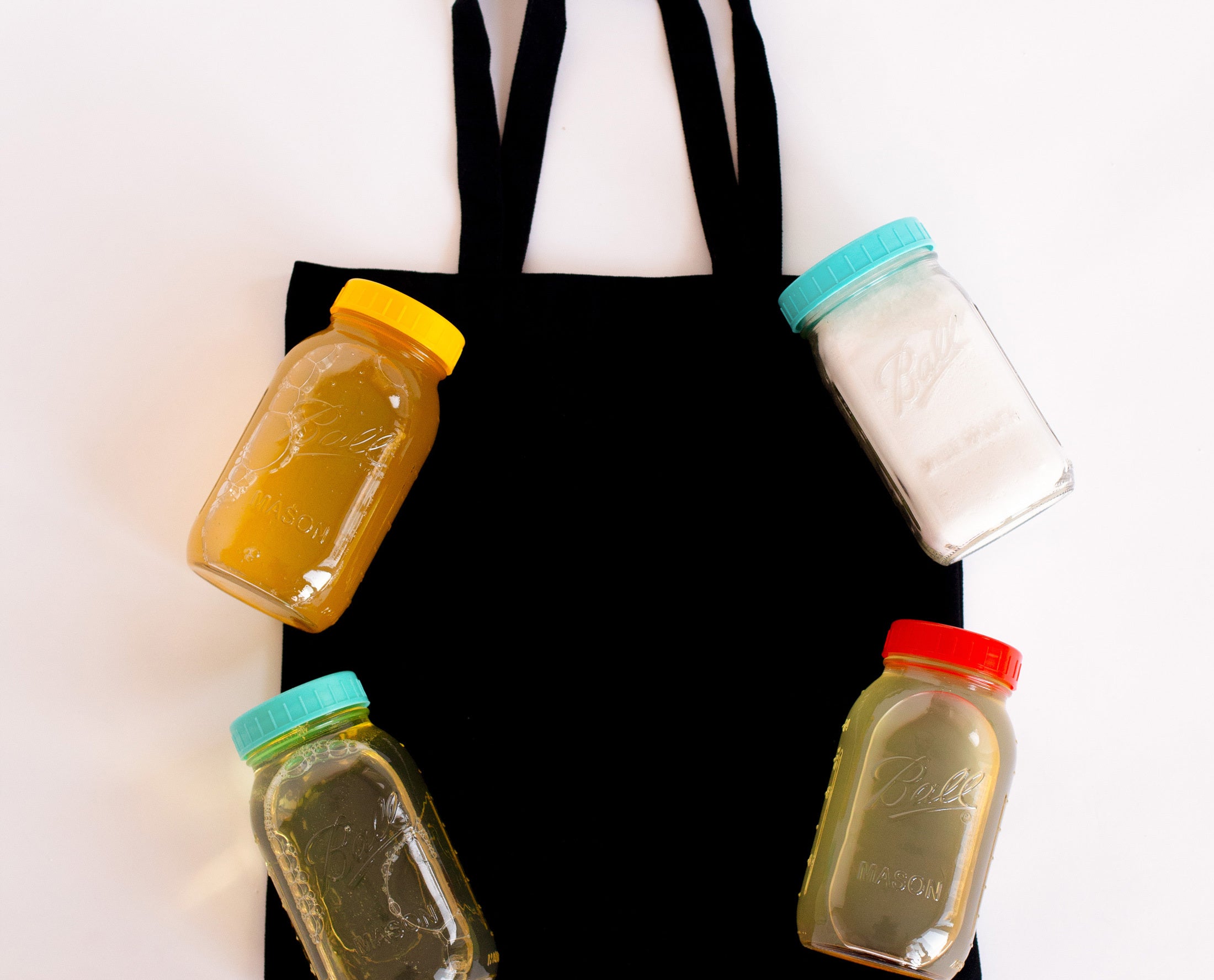 Black tote bag with colourful jars of various soaps laid across.