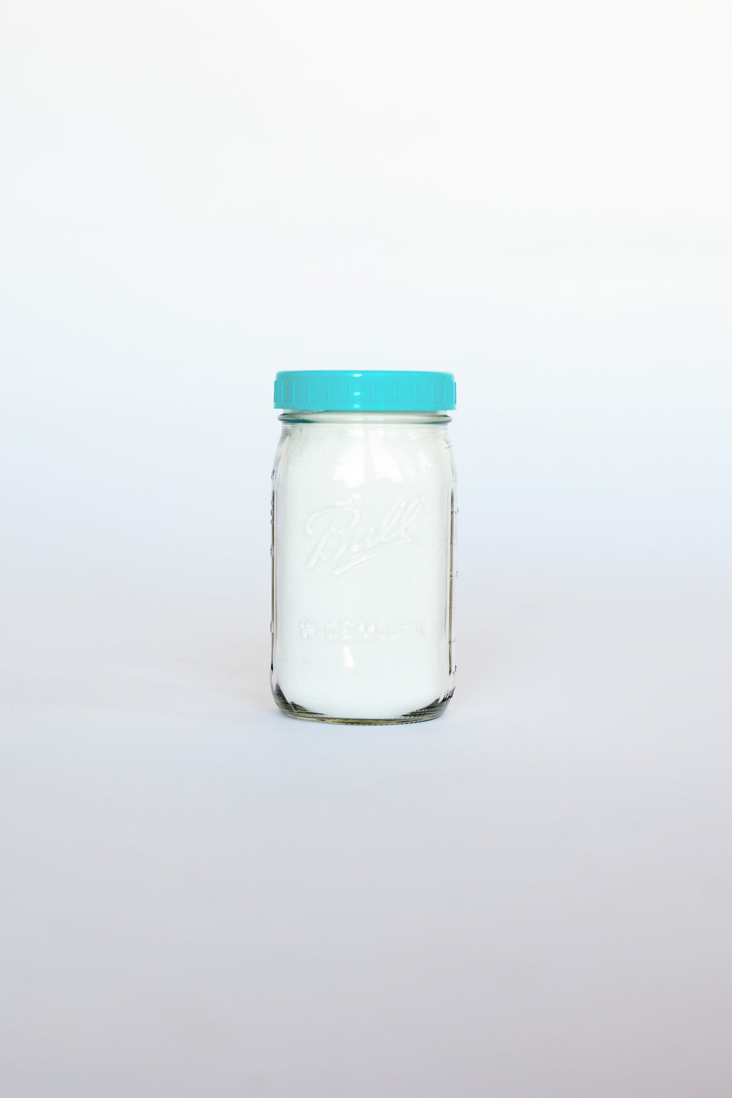 Clear glass jar with a green lid containing a white powdered soap on a white background